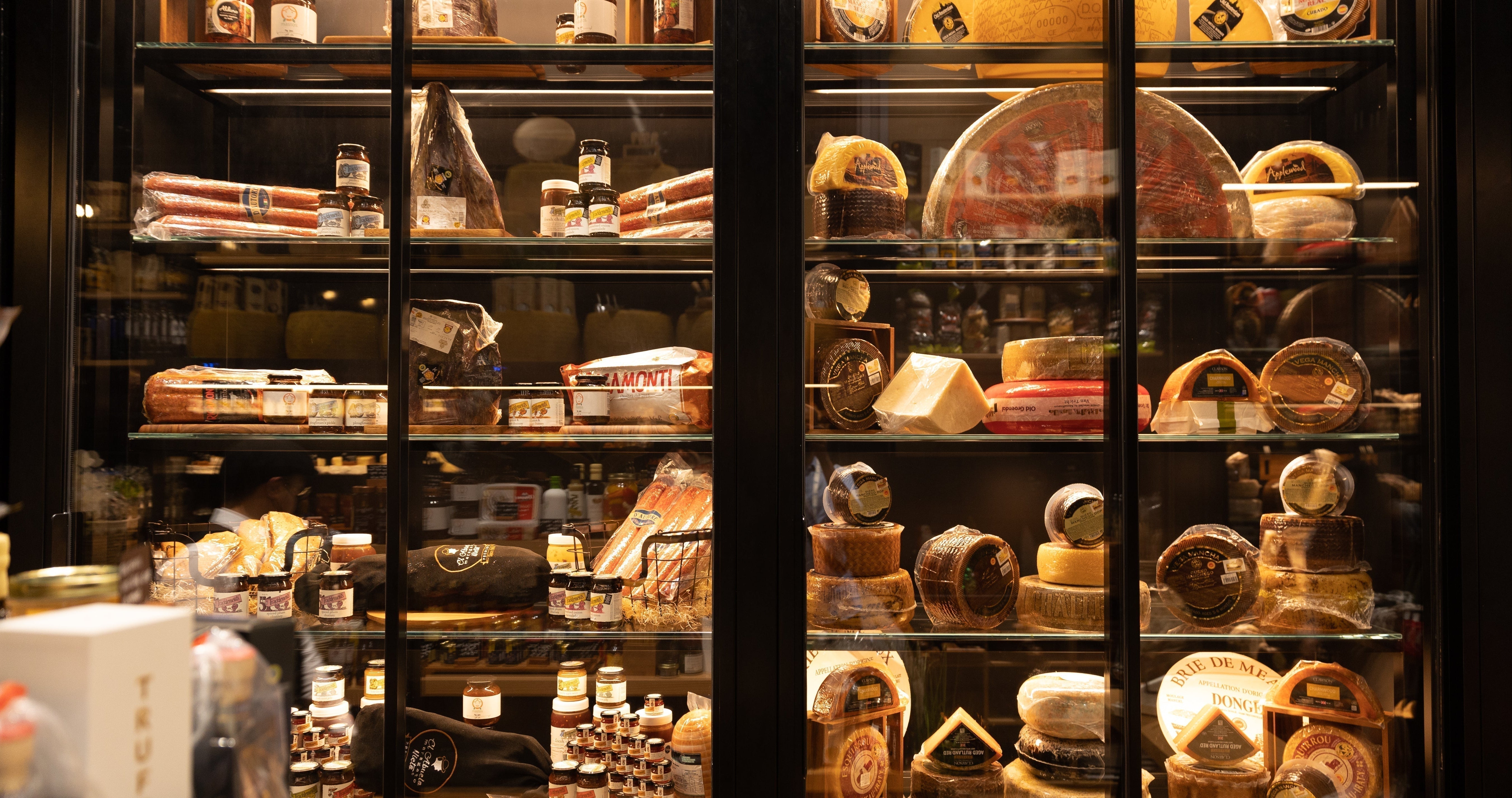 Display fridge at The Cheeseroom in Dubai showcasing artisanal cheeses, charcuterie, truffle products, and gourmet condiments in a luxury cheese boutique.